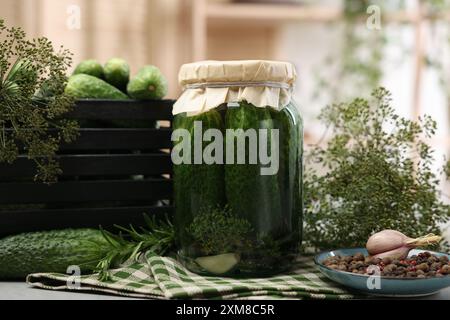 Concombres marinés en pot, herbes et épices sur la table, gros plan Banque D'Images