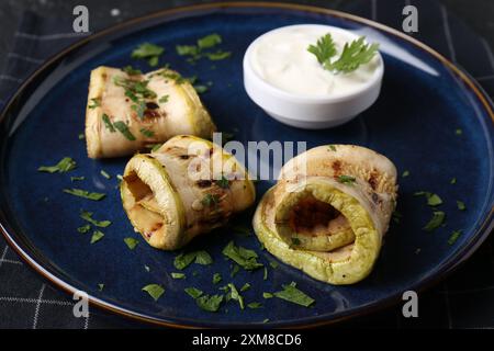 Savoureuses tranches de courgettes grillées servies avec sauce sur table, gros plan Banque D'Images