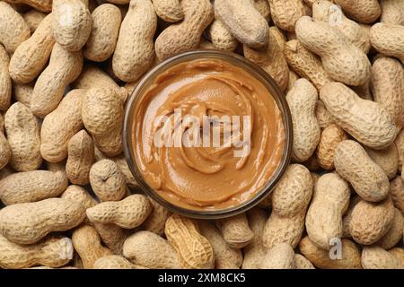 Savoureux beurre d'arachide dans un bol parmi les arachides, plat Banque D'Images