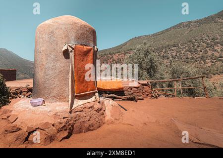 Une structure traditionnelle en pierre avec un sommet arrondi, situé dans un paysage rural de village berbère. La structure a une porte recouverte de tissu et de le Banque D'Images