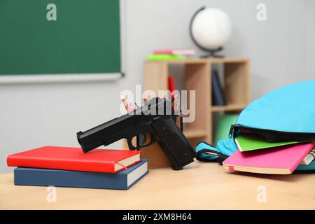 Papeterie scolaire, pistolet et sac à dos sur le bureau en classe Banque D'Images