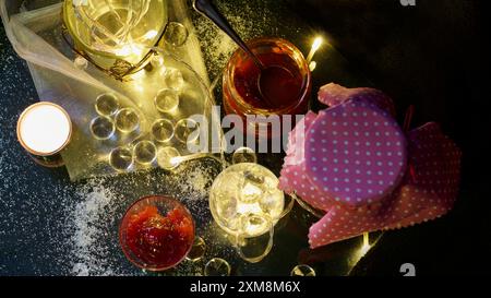 Verres avec marmelade de prunes maison, lumières de fées, bougie, cristaux de verre. Sensation d'automne atmosphérique, Banque D'Images