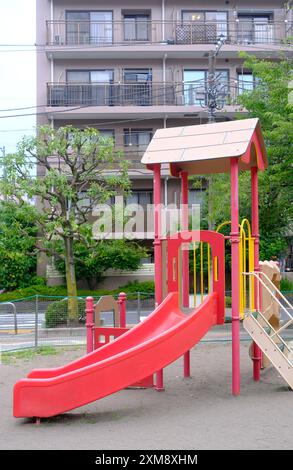 Le toboggan joyeux rouge pour enfant et enfants dans une aire de jeux résidentielle japonaise Banque D'Images