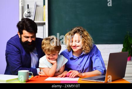 Premier jour à l'école. Leçon privée. Petit enfant étudiant leçon en classe. Les enseignants homme et femme aidant l'enfant de l'école primaire font les travaux scolaires Banque D'Images