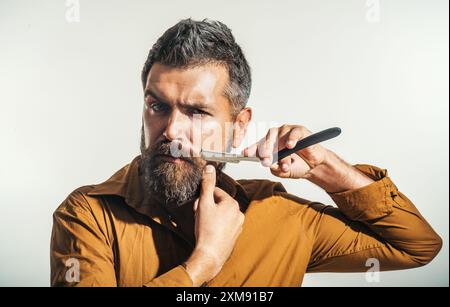 Coiffeur avec rasoir droit. Homme dans le rasage de barbier. Salon de coiffure, barbe, rasoir droit. Homme barbu portrait avec rasoir droit vintage. Moustache m Banque D'Images