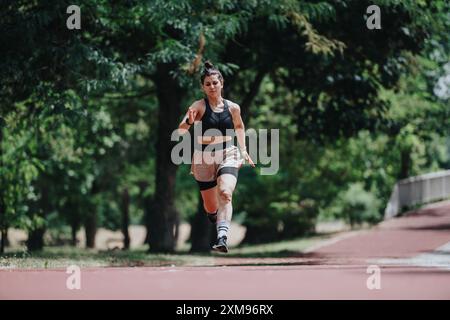 Coureuse féminine sprint sur une piste extérieure à travers le parc par une journée ensoleillée Banque D'Images
