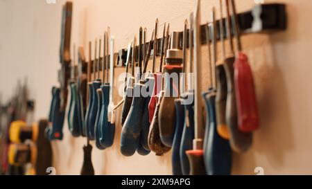 Ciseaux, tournevis, clé et pinces sur le mur dans l'atelier d'assemblage de meubles, plan panoramique. Gros plan de divers outils de travail du bois sur rack dans la menuiserie utilisée pour travailler avec des matériaux en bois Banque D'Images