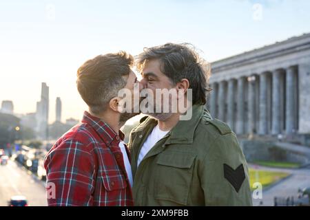 Couple gay hispanique s'embrassant au coucher du soleil dans la ville de Buenos Aires. Banque D'Images