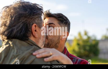 Gros plan d'un couple homosexuel marié s'embrassant chacun à l'extérieur Banque D'Images