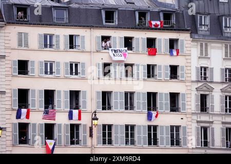 Paris, France. 26 juillet 2024. Cérémonies d'ouverture olympique. Les spectateurs regardent depuis les fenêtres de l'appartement le long de la Seine en attendant l'arrivée de bateaux transportant des athlètes lors des cérémonies d'ouverture des Jeux Olympiques de Paris 2024. Crédit : Adam Stoltman/Alamy Live News Banque D'Images