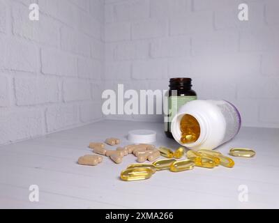 Bouteilles de supplément ouvertes avec des pilules dispersées et des capsules sur un fond de mur de briques blanches Banque D'Images