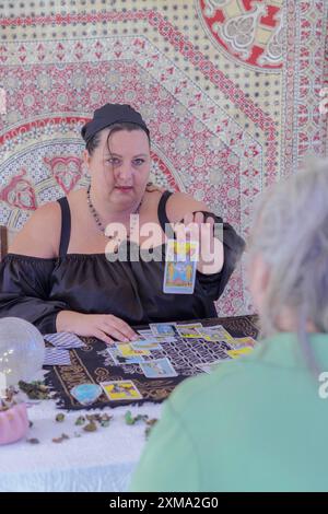 Tzigane diseuse vêtue de noir montrant une carte de tarot à son client dans une lecture de tarot Banque D'Images