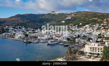 Vue panoramique d'une ville côtière sur une île grecque avec des bâtiments blancs et des collines s'étendant à la mer, Skala, Patmos, Dodécanèse, îles grecques Banque D'Images