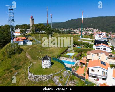 Maisons et moulin à vent sur une colline avec antennes environnantes et un petit village en arrière-plan, vue aérienne, phare, moulin, Montedor, Viana Do Banque D'Images