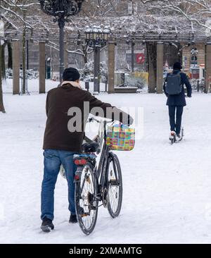 Hiver dans la ville, cycliste pousse son vélo sur la couverture de neige fermée devant l'opéra, pilote de scooter électrique, Francfort-sur-le-main, Hesse, Allemagne Banque D'Images