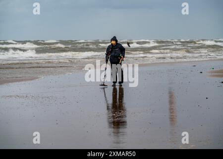 Chasseur de trésors, homme avec détecteur de métaux sur la plage, nuages sombres, automne en mer du Nord en Hollande du Nord, près d'Egmond aan Zee, pays-Bas Banque D'Images