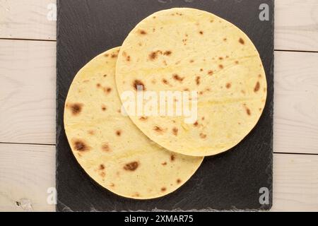 Deux tacos savoureux avec pierre d'ardoise sur table en bois, macro, vue de dessus. Banque D'Images