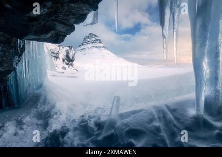 Kirkjufell montagne pendant l'hiver au lever du soleil, tourné derrière la cascade gelée, glaçons au premier plan, vue originale, belle journée, paysage nat Banque D'Images