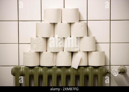 Rouleaux de papier toilette empilés sur un radiateur dans une toilette publique Banque D'Images