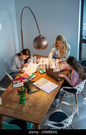Homeschooling, pendant le confinement en janvier 2021, mère aide ses deux filles, à la maison, à apprendre, avec des manuels et des ordinateurs, des fermetures d'écoles Banque D'Images