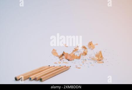 Une pile de copeaux de crayon se trouve sur un fond blanc. Les crayons sont disposés en rangée, avec les copeaux dispersés autour d'eux. Concept de désordre Banque D'Images