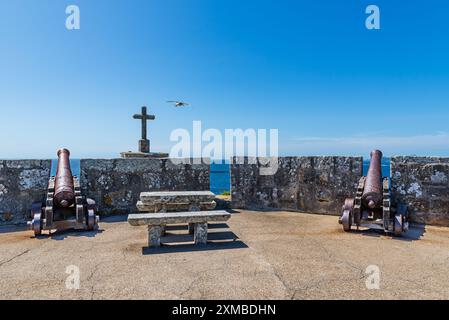 Anciens canons sur les remparts du château de Monterreal à côté d'une croix de pierre, Baiona. Banque D'Images