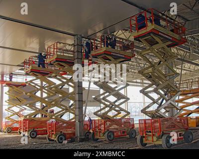 Kiev, Ukraine. 03 décembre. 2011. Plusieurs élévateurs à ciseaux utilisés par les ouvriers du bâtiment pour installer des panneaux de plafond dans une grande installation industrielle. Banque D'Images