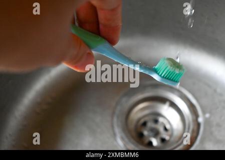 l'eau coule le long de la brosse à dents et tombe dans l'évier Banque D'Images