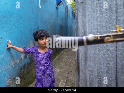 Fille bangladaise dans la rue regardant un musicien jouant de la trompette, Dhaka Division, Munshiganj Sadar, Bangladesh Banque D'Images