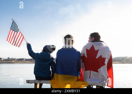 Famille avec drapeau canadien, drapeaux ukrainien et américain à l'extérieur. Voyages, immigration. Soutien international à l'aide à l'Ukraine pour gagner la guerre Banque D'Images