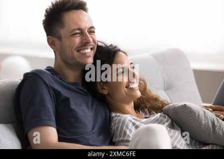 Couple se relaxant sur le canapé riant tout en regardant un film de comédie Banque D'Images
