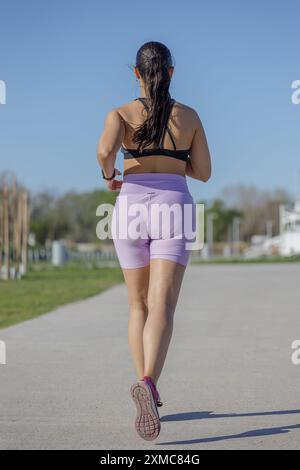 Fille latine courant dans un parc public vue de l'arrière. Banque D'Images