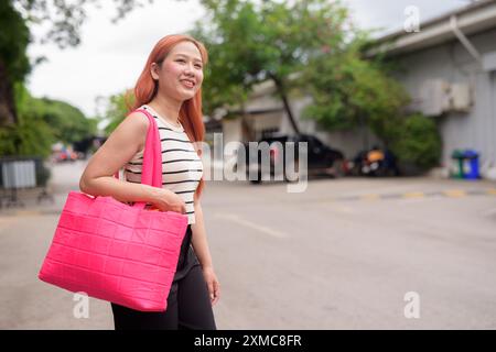 Portrait de belle femme asiatique tenant le sac à provisions rose brillant à l'extérieur pendant l'été Banque D'Images