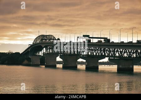 Port d'Auckland, Nouvelle-Zélande - trafic traversant le pont du port d'Auckland au coucher du soleil. Il s'agit d'un pont autoroutier sur le port de Waitematā Banque D'Images