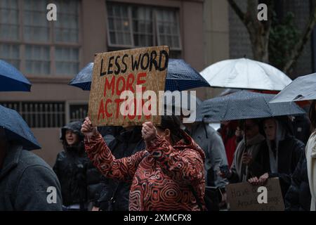 Melbourne, Australie. 27 juillet 2024. Un manifestant tient une pancarte qui dit « moins de mots plus d'action » pendant la manifestation. Malgré la pluie, les gens se sont rassemblés pour protester contre les violences faites aux femmes, après que 54 femmes ont été tuées cette année en raison de violences domestiques, les auteurs de ces violences étant principalement des hommes. Les manifestants appellent le gouvernement australien à agir. Crédit : SOPA images Limited/Alamy Live News Banque D'Images