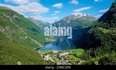 Une vue imprenable sur un fjord norvégien entouré de montagnes verdoyantes, avec un petit village niché au bord de l'eau. Geiranger Fjord Norvège Banque D'Images