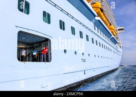 Nice, France : bateau pilote portuaire approchant l'HYMNE géant DES MERS du Royal Caribbean pour débarquer pilote maritime à Villefranche sur mer. Une escale unique pour le plus grand bateau de croisière cette année dans le petit port de la Côte d'Azur. Après la saison estivale, l'impressionnant navire devait naviguer à travers le canal de Suez dans le cadre d'un repositionnement de l'Europe vers un nouveau port d'attache à Singapour, mais à la suite des tensions de la mer Rouge et des menaces d'attaques de missiles Houthi sur les navires, il transportera plutôt sans passager autour de la pointe sud de l'Afrique pour rejoindre Dubaï et l'Asie. Crédit : Kevin Izorce/Alamy Live News Banque D'Images