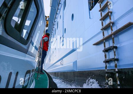 Nice, France : bateau pilote portuaire approchant l'HYMNE DES MERS géant de Royal Caribbean pour embarquer le pilote maritime à Villefranche sur mer. Une escale unique pour le plus grand bateau de croisière cette année dans le petit port de la Côte d'Azur. Après la saison estivale, l'impressionnant navire devait naviguer à travers le canal de Suez dans le cadre d'un repositionnement de l'Europe vers un nouveau port d'attache à Singapour, mais à la suite des tensions de la mer Rouge et des menaces d'attaques de missiles Houthi sur les navires, il transportera plutôt sans passager autour de la pointe sud de l'Afrique pour rejoindre Dubaï et l'Asie. Crédit : Kevin Izorce/Alamy Live News Banque D'Images