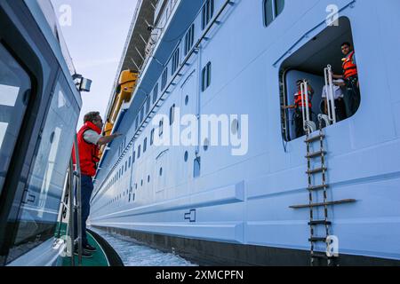 Nice, France : bateau pilote portuaire approchant l'HYMNE DES MERS géant de Royal Caribbean pour embarquer le pilote maritime à Villefranche sur mer. Une escale unique pour le plus grand bateau de croisière cette année dans le petit port de la Côte d'Azur. Après la saison estivale, l'impressionnant navire devait naviguer à travers le canal de Suez dans le cadre d'un repositionnement de l'Europe vers un nouveau port d'attache à Singapour, mais à la suite des tensions de la mer Rouge et des menaces d'attaques de missiles Houthi sur les navires, il transportera plutôt sans passager autour de la pointe sud de l'Afrique pour rejoindre Dubaï et l'Asie. Crédit : Kevin Izorce/Alamy Live News Banque D'Images