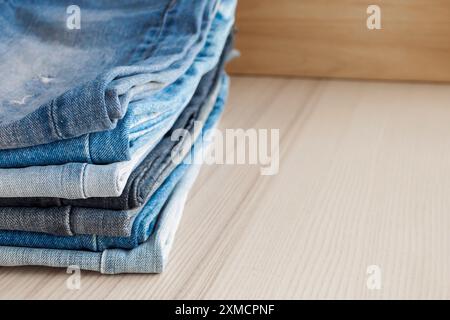 jeans bleu denim empilés sur fond de table en bois Banque D'Images