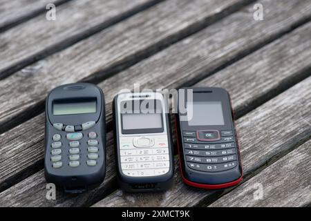 Téléphones portables obsolètes sur une vieille table en bois vieillie Banque D'Images