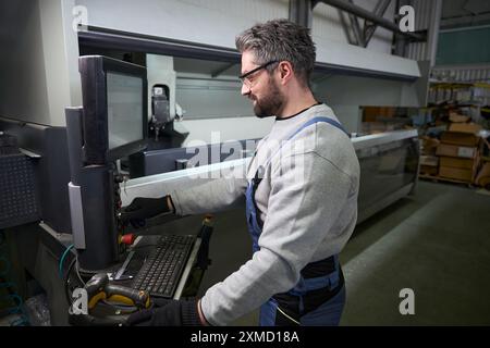 L'homme utilise un ordinateur moderne dans un atelier de production Banque D'Images