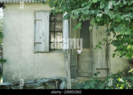 Fenêtre et porte en bois d'une maison abandonnée dans le village de Donja Crnuca, Sumadija, Serbie centrale (pas de boîte aux lettres, courrier coincé dans la porte fermée) Banque D'Images