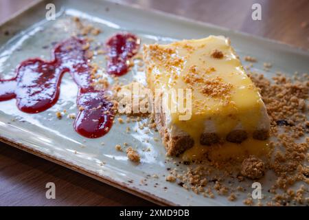 Un dessert avec une sauce et des miettes servi sur une longue assiette avec une sauce framboise. Banque D'Images