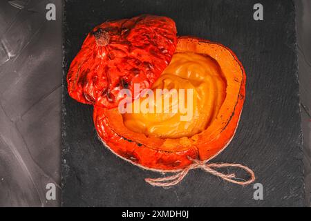 Citrouille cuite remplie de soupe, purée de pommes de terre sur un plateau de mica noir. Présentation exquise du plat. Photo de haute qualité Banque D'Images