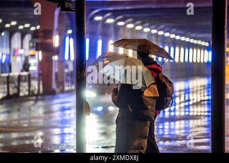 Métro éclairé à la gare principale, piétons à un passage piéton, temps pluvieux, centre-ville, le soir, Essen, Nord Banque D'Images
