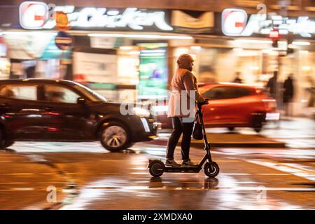 Rue à la gare principale, chauffeur de scooter électrique, temps pluvieux, centre-ville, le soir, Essen, Rhénanie du Nord-Westphalie, Allemagne Banque D'Images