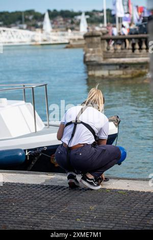 jeune femme attachant un bateau à la régate cowes week à cowes sur l'île de wight, employé de l'escadron royal de yacht Banque D'Images