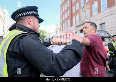 Londres, Royaume-Uni, 27 juillet 2024. Un homme se dispute avec un policier alors que plusieurs personnes sont arrêtées devant les pubs de Whitehall après la fin du rassemblement pro-britannique Tommy Robinson. Un certain nombre de pubs fermés dans la partie supérieure de la rue la plus proche de Trafalgar Square. Crédit : onzième heure photographie/Alamy Live News Banque D'Images