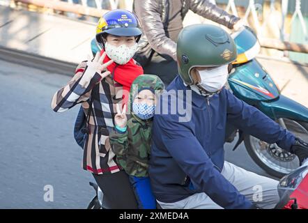 Femme et enfant vietnamiens chevauchant un cyclomoteur sur le pont de long bien et agitant devant la caméra, Hanoi, Vietnam Banque D'Images